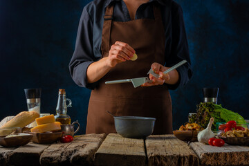 The chef prepares a classic Caesar salad. He crushes the garlic through a sauce press. Lots of ingredients. Beautiful composition. Restaurant, hotel, recipe book, step by step recipe.