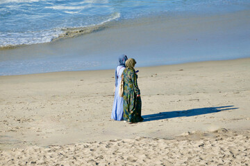 Tow women wearing burkas taking a morning stroll on the beach