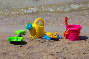 Fototapeta na wymiar Multicolored children's toys on the beach. Children's vacation at sea.