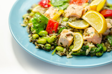 Pieces of cooked salmon and edamame soya beans with red pepper  and baby leaf spinach, served with brown long grain rice with lemon peel and ginger, soya, honey and black fungus mushroom sauce