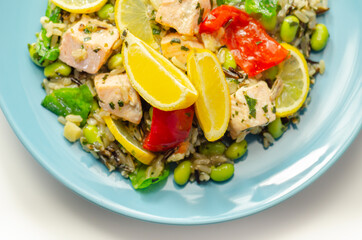 Pieces of cooked salmon and edamame soya beans with red pepper  and baby leaf spinach, served with brown long grain rice with lemon peel and ginger, soya, honey and black fungus mushroom sauce