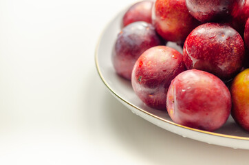 Closeup on fresh and ripe plums on a white ceramic plate