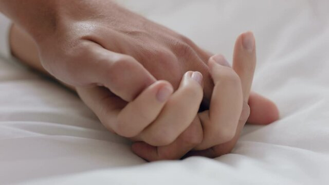 close up young couple holding hands lying in bed together enjoying romantic relationship 4k footage