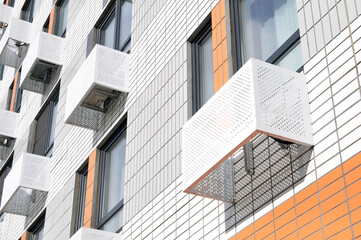 The facade of a new multi-storey residential building with windows and compartments for outdoor units of split systems.
