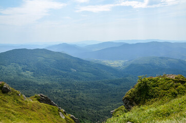 Naklejka premium Carpathians mountain hills, covered rocks and grassy slope with forest and mountain range. beautiful summer landscape. Ukraine