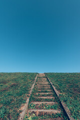 stairs up outdoors with grass around to the sky, blue and green colors