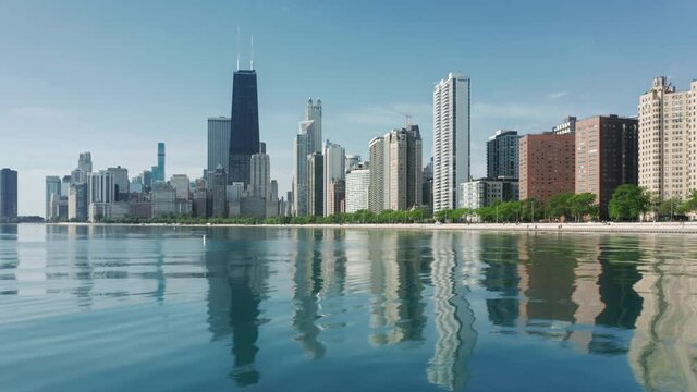Luxury residential front line buildings with beautiful Michigan lake view with Chicago downtown skyscrapers reflecting in clear still water. Background for travel, Illinois USA. 4K Chicago panorama