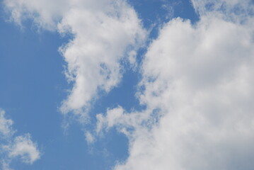 Light white fluffy clouds. Against the background of a light blue sky, a snow-white cloud in a light solar haze. A cloud surrounds the blue of the sky.