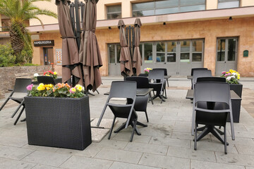 Chairs and tables collected left on the sidewalk in front of a closed restaurant hamburgery