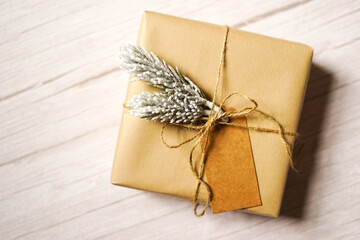 Christmas present wrapped in natural brown paper on light wooden background. Natural sustainable...