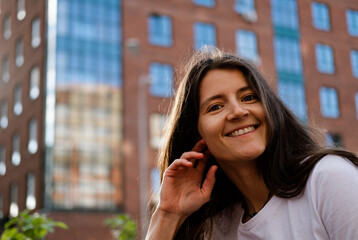 Beautiful young brunette on the background of the city. Happiness expression emotional  lifestyle portrait. - obrazy, fototapety, plakaty