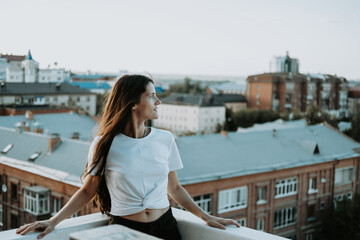 Happy young brunette lifestyle portrait. Woman standing on roof.