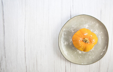 Orange pumpkin on white wooden background with copy space on natural plate top view, autumn harvest, Halloween or Thanksgiving concept
