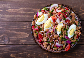 Plate with piyaz salad on a brown wooden background. Free space.