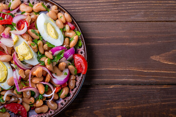 Plate with piyaz salad on a brown wooden background. Free space.