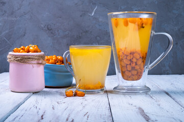Sea buckthorn and sea buckthorn tea in a bowl on a gray background.