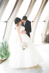 Fototapeta premium Lovely happy wedding couple, bride with long white dress posing in beautiful city