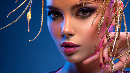 Stylish fashion model with a golden decoration around her face. Beauty style. Art portrait of a...