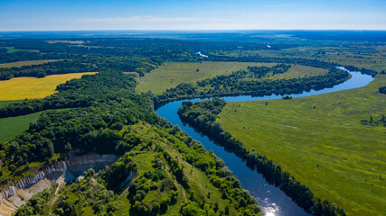 Fototapeta na wymiar Aerial view of a beautiful summer landscape over river. Wide green valley with a river running in the middle. Green meadows. Top view over beauty nature.