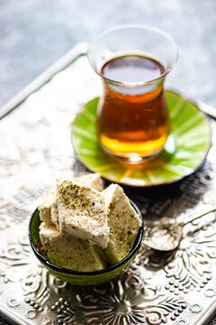 Cup of traditional  Turkish sweet tea with a bowl of pistachio halva on a metal tray
