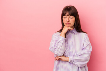 Young curvy caucasian woman isolated on pink background looking sideways with doubtful and skeptical expression.