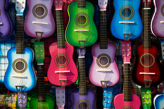 Sunlit, Angular, Isolated View of Colorful Small Children's Guitars Hanging Up