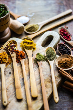 Wooden Spoons On A Chopping Board Filled With Assorted Dried Spices And Seasoning