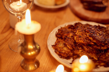 Potato latkes, traditional Jewish food on dining table during Hanukkah dinner.