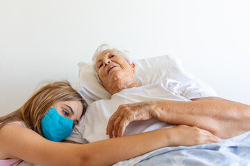 Mulher idosa doente de cama após queda com braço quebrado recebe carinho de neta no leito 