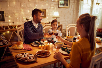 Happy Jewish family toasts during Hanukkah traditional dinner at dining table.