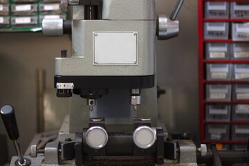 Grey key duplicating machine in a hardware store with key boxes in the background.