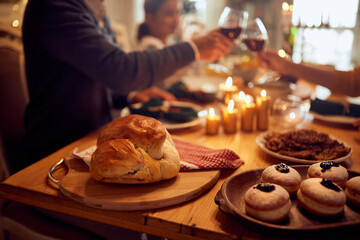 Close-up of traditional Hanukkah food with family toasting in background.