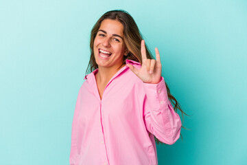 Fototapeta premium Young caucasian woman isolated on blue background showing a horns gesture as a revolution concept.
