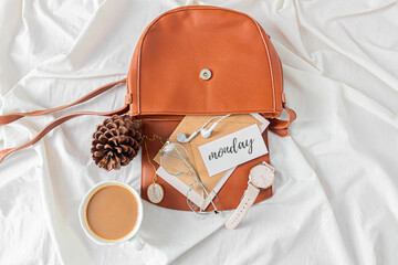 Fashion composition with female accessories and stationary on messy bed background. Bag with kraft...