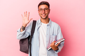 Young caucasian student man holding books isolated on pink background  smiling cheerful showing...