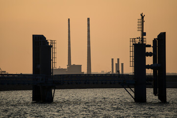 Beautiful telephoto view Poolbeg CCGT chimneys and Pigeon House Powers Station between wingwalls of St Michael pier ferry terminal in Dun Laoghaire harbor, Dublin, Ireland. Soft and selective focus