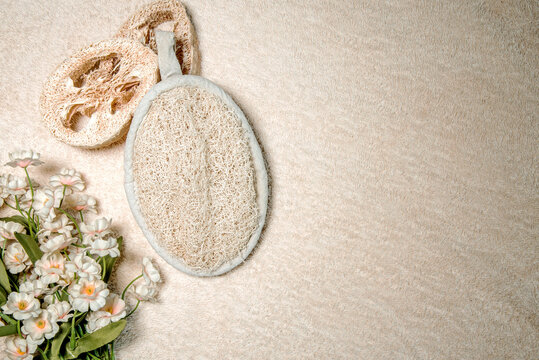 Esponja de lufa y dos discos cortados de lufa sobre un fondo beige con flores. Cambios para un ba&ntilde;o cero residuos sin pl&aacute;stico.