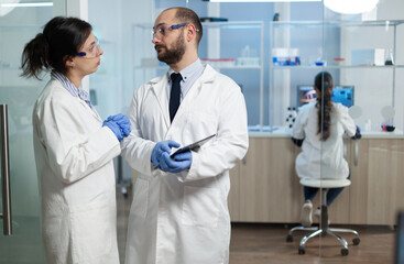 Fototapeta premium Scientist woman analyzing virus expertise with biologist researcher dicussing prevention treatment during clinical examination in microbiology hospital laboratory. Sickness investigation