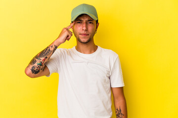Young caucasian man with tattoos isolated on yellow background  pointing temple with finger, thinking, focused on a task.