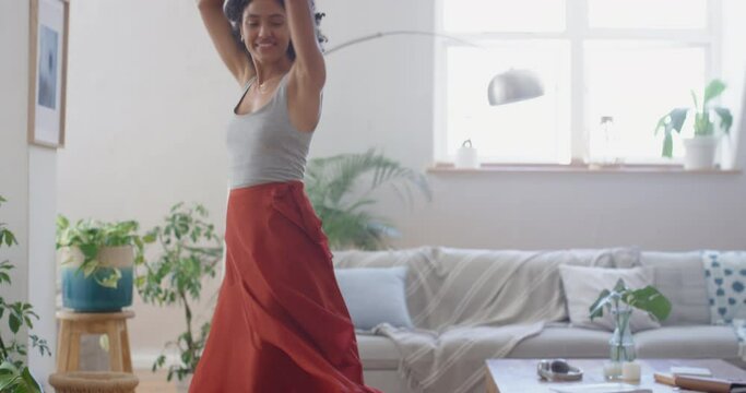 happy african american woman dancing at home wearing beautiful red dress celebrating having fun enjoying summer feeling confident 4k footage