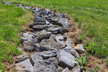 Path of large gray rocks in the middle of field of green grass. - Powered by Adobe