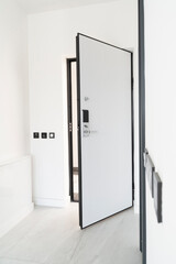 Modern and bright apartment entrance with elegant white door equipped with high tech lock system.
