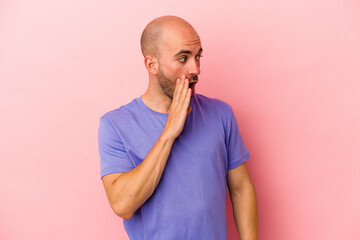 Young caucasian bald man isolated on pink background  being shocked because of something she has seen.