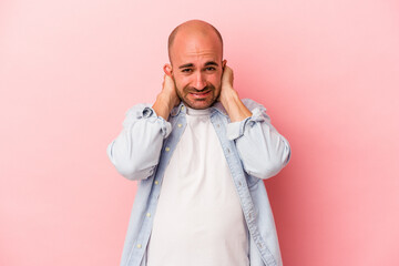 Young caucasian bald man isolated on pink background  screaming with rage.