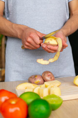 close up of a man peeling a potato over a wood cutting board
