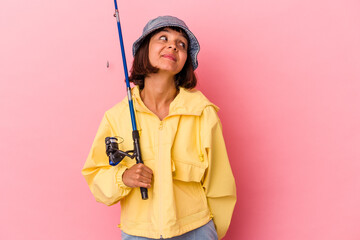 Young mixed race woman practicing fishing isolated on pink background dreaming of achieving goals and purposes