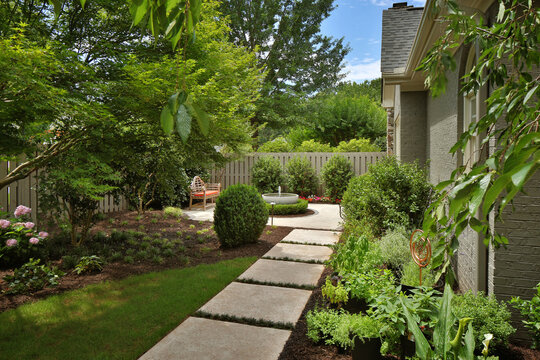 Stone path in garden leading to backyard water fountain and patio