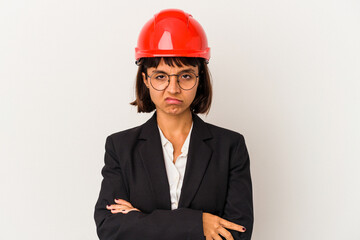 Young architect woman with red helmet isolated on white background frowning face in displeasure, keeps arms folded.