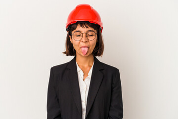 Young architect woman with red helmet isolated on white background funny and friendly sticking out tongue.