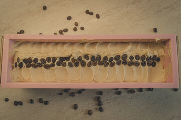 Naklejka premium Preparation of handmade soap. The base for soap in silicone form, decorated with coffee beans. Top view, horizontal composition, copy space, color toning